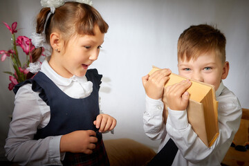 A schoolboy and schoolgirl in uniform having fun and rest with book in the room. A boy and girl during fun photo shoot about school. September 1 holiday in Russia