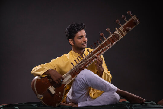 Portrait of young man performing with Sitar at concert