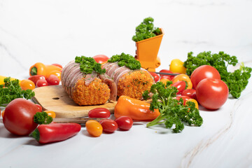 minced meat sausages in bacon with green parsley and fresh vegetables, cherry 