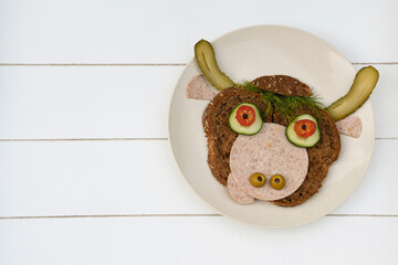 Sandwich iof a cheerful bull made of dark bread, sausages and vegetables 