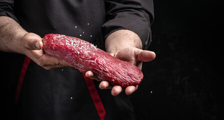 Chef salts steak in a freeze motion with rosemary and spices. Preparing fresh beef or pork on a...