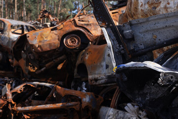 bracelet as symbol of ukraine - flag from blue and yellow with burnt out cars on background from russian attack. russian military war crimes against ukraine. glory to ukraine