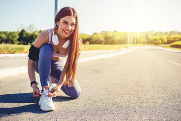 Close up of sporty woman tying shoelace while kneeling outdoor. young woman runner tying her shoes...