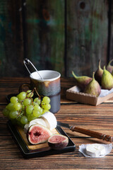 cheese plate with goat cheese, grapes and figs, copper teapot, angle view
