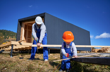 Father with toddler son building wooden frame house in the Scandinavian style barnhouse. Male...