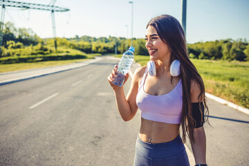 Shot of a sporty young woman drinking water outdoors. Photo of young Woman drinking water from bottle. Caucasian female drinking water after exercises or sport.