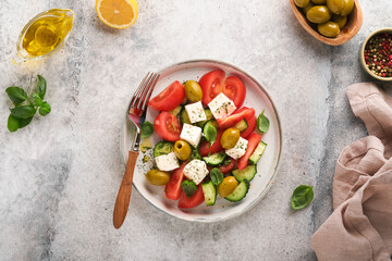 Greek salad. Fresh Greek salad with fresh vegetables, tomato, cucumber, green olives and feta cheese on old grey concrete table background. Top view.