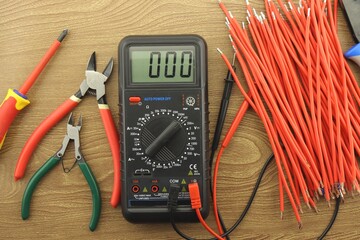 Multimeter and mounting tools on a wooden background close-up.