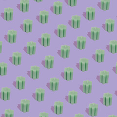 Colorful, bright pattern made with green handmade soy wax candle on purple background. Fun modern concept.