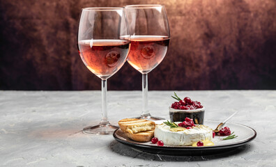 Baked camembert cheese with cranberries, basil leaves and rosemary with wine on light table. French cuisine. Food recipe background. Close up