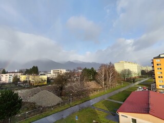 Fototapeta na wymiar Rainbow in the city over eht hills and houses. Slovakia
