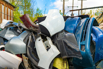 A group of plastic fiber car bumpers in a car junkyard. Plastic raw materials, collection of...