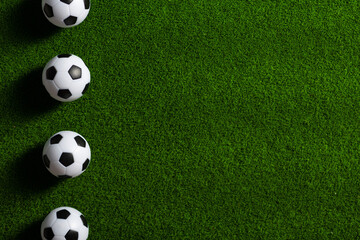 Several soccer balls on a green grass field. Start Qatar 2022.