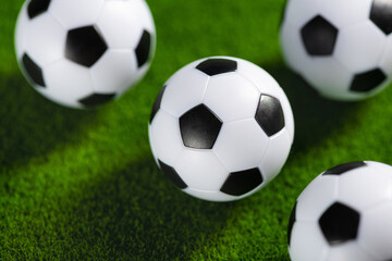 Several soccer balls on a green grass field. Start Qatar 2022.