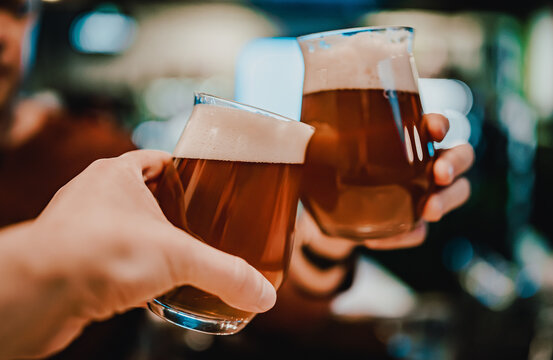 Two friends hands toasting with glasses of light beer at the pub or bar. taproom