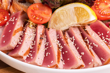 Tuna steak cut into pieces with lemon and tomato