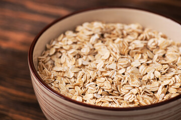 Bowl with oatmeal flakes on a wooden background
