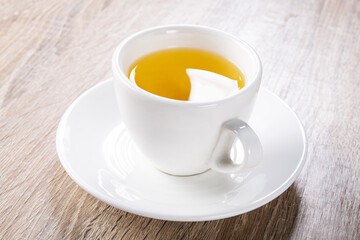 Hot yellow herbal tea in a white cup