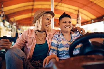 Deurstickers Cheerful female couple has fun in bumper car at amusement park. © Drazen