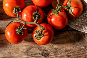 Closeup of branch tomatoes on an aged wooden table.