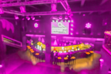 Blurred modern abstract interior of a nightclub with neon purple lighting on the walls