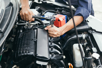 Automobile mechanic repairman hands repairing a car engine automotive workshop with a wrench, car...