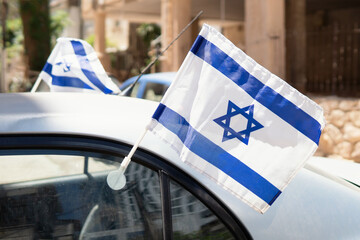 Israel flags waving in the wind attached to the car window outdoors. Celebrating independence day...
