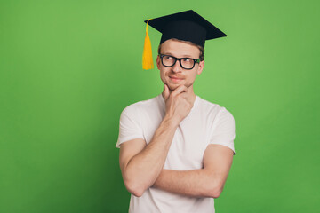 Photo of clever student man think look empty space wear mortar board cap glasses on green color...