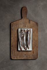 Still life with raw fish on a rustic wooden board. Top view.