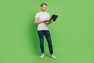 Photo of confident freelancer business man hold netbook typing code bug wear white t-shirt on green color background