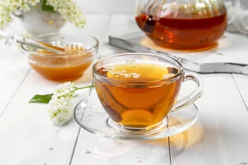 Foto op Plexiglas Useful spring tea with bird cherry in a transparent cup on a light background © 02irina