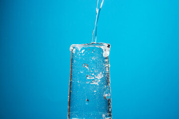 Water is poured into a glass on a blue background. Pure drinking water.