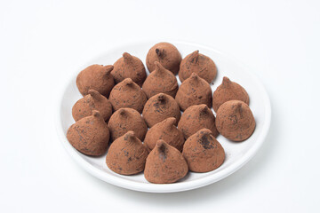 Chocolate truffle sweets on a saucer on a white background. Delicious chocolate dessert.