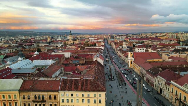 Aerial drone view of Cluj centre at sunset, Romania. Cityscape, walking people, road with cars, old buildings