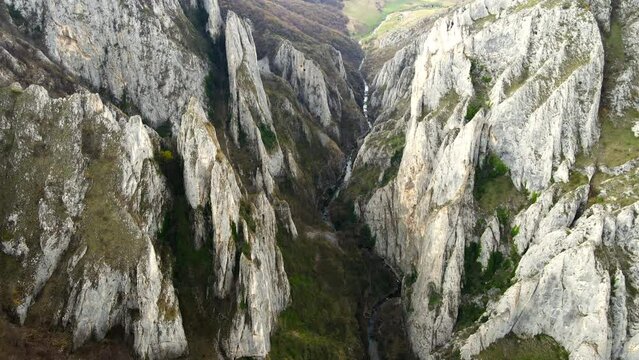 Aerial drone view of a rocky canyon in Romania. Rocky cliffs with sparce vegetation. Fields and hills around