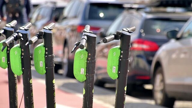 Row of electric scooters for sharing on the street in Cluj, Romania. Cars on the background