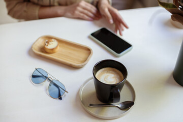 a cup of coffee, a smartphone and glasses on the table in a coffee shop. blog