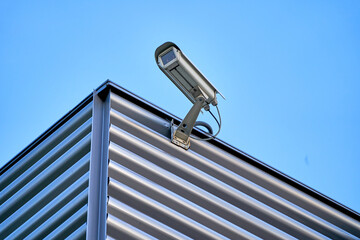 Security camera on a modern office building. Clean blue sky.