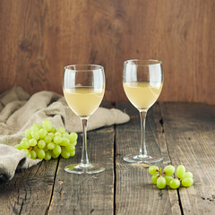 Delicious white wine in shiny glasses and grapes on table