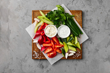 Assorted cut vegetables with sauces and herbs on stone table
