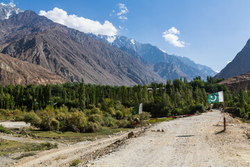 Beautiful landscapes of Hindukush mountains. Road through mountain ranges and green villages, check-point with Pakistani flags. Pakistan