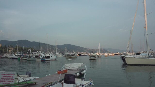 RAPALLO, LIGURIA, ITALY - AUGUST 22, 2018: Boats and yachts at the mooring in Rapallo at summer sunset, Italy. 2K, Editorial. Wide shot, Pan