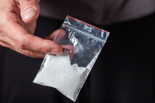 Concept drug addiction. Man hand holds plastic packet or bag with cocaine or another drugs