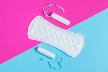 women pads and tampon - sanitary pads lies next to a tampon on an isolated background on a pink and blue background.