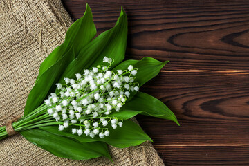 Small and fragrant spring flowers. Bouqet of lily of the valley flowers on dark wooden background