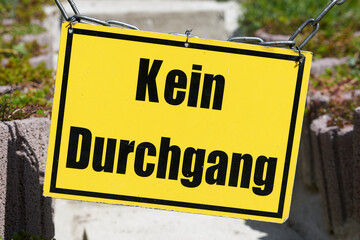 gelbes Schild an einem gesperrten Fußweg mit der Aufschrift kein Durchgang