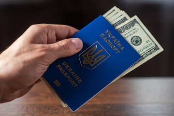Ukrainian biometric passport and dollars. Ukrainian passport on a wooden background, top view. Document for traveling