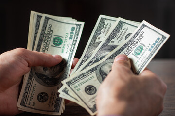 a man holds stack hundred-dollar bills in his hands close-up.