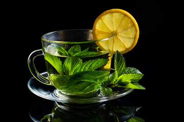 Hot cup of tea with fresh mint leaf on black background