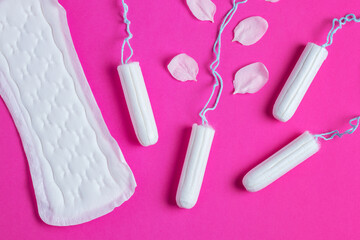 Female tampons with with cherry petals and woman gasket on a pink background. Hygienic white tampon for women. - obrazy, fototapety, plakaty